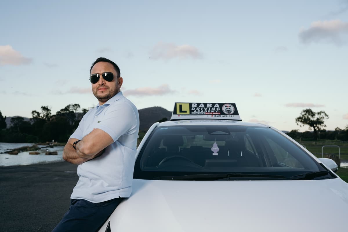 Indra Khadka beside the Baba Driving Academy training car in Tasmania.