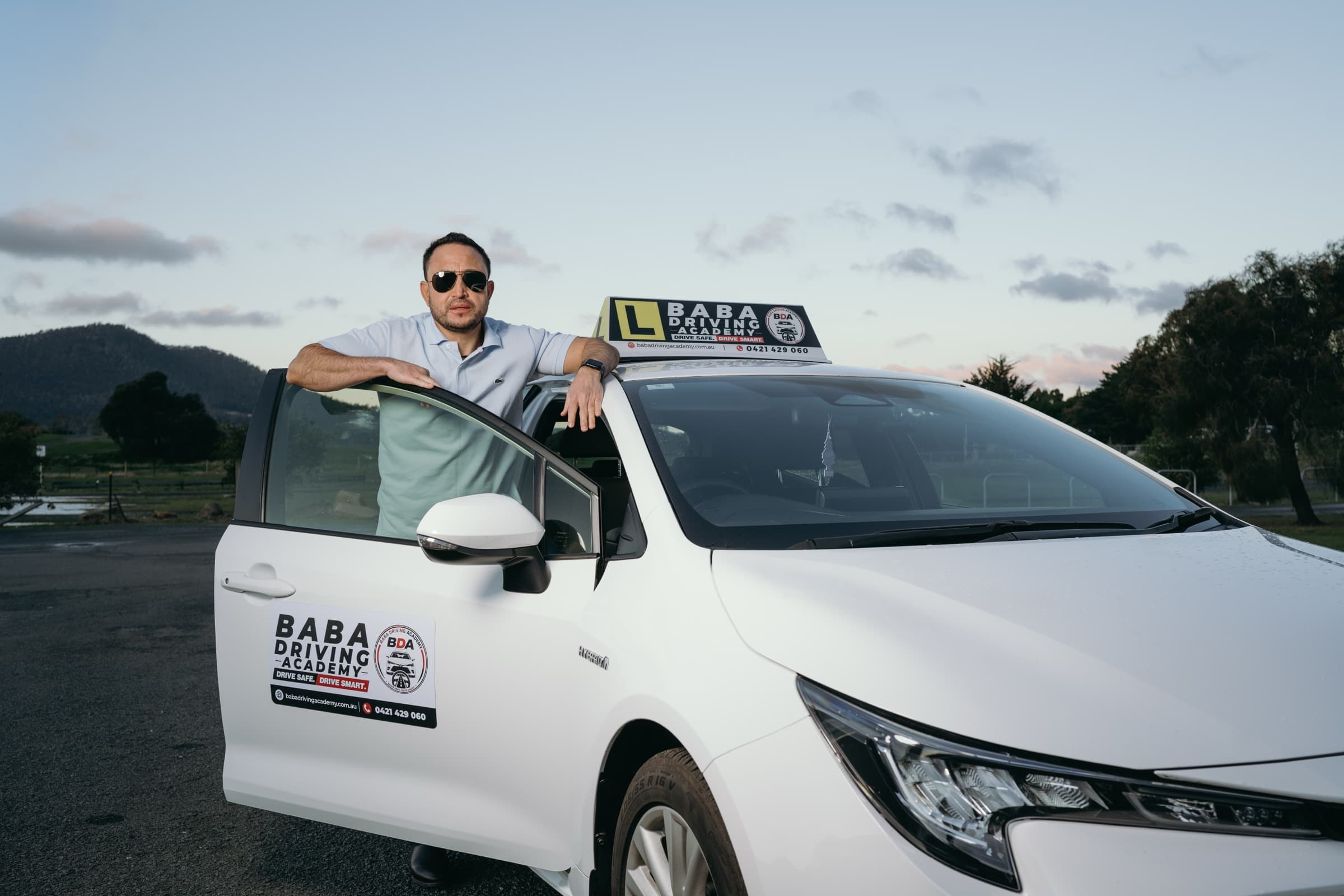 Indra Khadka, Australian Certified Driving Instructor at Baba Driving Academy, standing by the training vehicle.