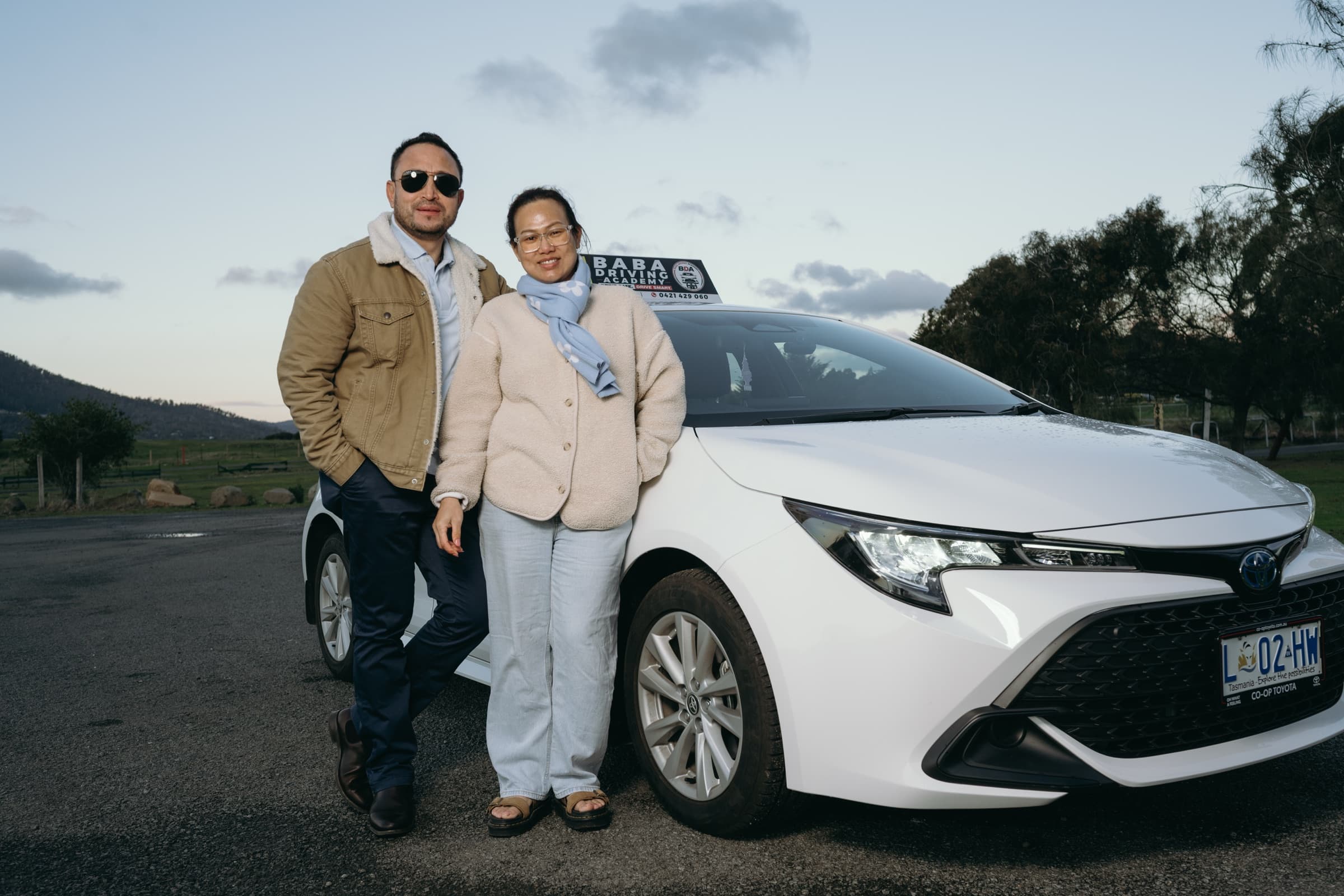 Instructor with a learner beside the Baba Driving Academy car in Tasmania
